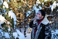 brutal man with beard in warm sheepskin coat washes his face with snow in forest.