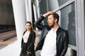 A brutal man in a black leather jacket straightens his hair on his head with his hand, his woman stands behind him Royalty Free Stock Photo