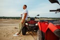 Brutal man poses near atv in desert, quadbike Royalty Free Stock Photo