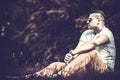 Brutal man in sunglasses sitting on the ground outdoor Royalty Free Stock Photo