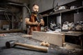 Brutal master carpenter in an apron adjusts plane in workshop