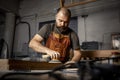 Brutal master carpenter grinds wooden blanks with machine in workshop