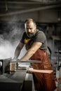 Brutal master carpenter saws wood blanks on machine in workshop