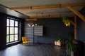 Brutal modern interior in a dark color with a leather sofa and large window. Loft style living room