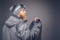 Brutal redhead snowboarder with a full beard in a winter hat and protective glasses dressed in a snowboarding coat