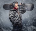 Brutal redhead snowboarder with a full beard in a winter hat and protective glasses dressed in a snowboarding coat