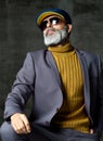 Brutal senior white bearded man in classic grey suit, green sweater, cap and aviator sunglasses stylish fashionable men Royalty Free Stock Photo