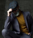 Brutal senior white bearded man in classic grey suit, green sweater, cap and aviator sunglasses stylish fashionable men Royalty Free Stock Photo