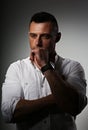 Brutal serious business man thinking in white style shirt on grey dark shadow background. Closeup portrait