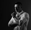 Brutal serious business man thinking in white style shirt on grey dark shadow background. Closeup portrait. Black and white