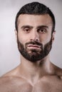 Brutal strong bodybuilder man posing in studio on grey background.