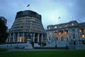 Modern expansion of conic Beehive in gray concrete to old Edwardian parliament illuminated at dusk, Wellington, New Zealand Royalty Free Stock Photo