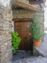 Brwon wooden front door with metal doorknocker stone wall and plants in spain Royalty Free Stock Photo