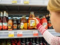 Bryansk, Russia - December 20, 2019: Girl chooses a drink. Showcase with juice bottles in the store Lenta