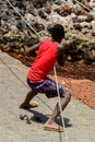 Unidentified local boy in red shirt pulls the rope in a village
