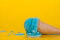 Bubble gum ice cream in a traditional cone on a yellow background. Melting with scattered drops Royalty Free Stock Photo