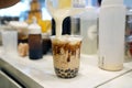 Bubble Milk Tea - Pouring cream cheese into glass of milk tea with black sugar syrup Kuromitsu and hot black pearl Boba topped