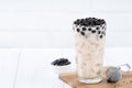 Bubble milk tea with tapioca pearl topping, famous Taiwanese drink on white wooden table background in drinking glass, close up,