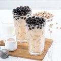 Bubble milk tea with tapioca pearl topping ingredient, famous Taiwanese drink on white wooden table