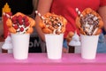 Bubble waffles with raspberries, chocolate, marshmallow and nuts in white paper cups are sold on food festival event. Royalty Free Stock Photo