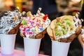 Bubble waffles with raspberries, chocolate and marshmallow in white paper cups are sold on Open kitchen food festival event. Royalty Free Stock Photo