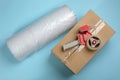Bubble wrap roll, cardboard box and tape dispenser on turquoise background, flat lay Royalty Free Stock Photo