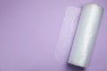 Bubble wrap roll on lilac background, top view. Space for text