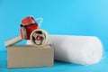 Bubble wrap roll, tape dispenser and cardboard box on light blue background Royalty Free Stock Photo