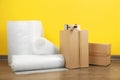 Bubble wrap rolls, tape dispenser and cardboard boxes on floor near yellow wall Royalty Free Stock Photo