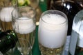 Bubbles coming off poured champagne in a foamy glass with surrounding bottle shapes and more champagne being poured