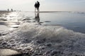 Bubbles of sea foam in the foreground and a blurry silhouette of a couple having fun Royalty Free Stock Photo