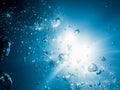 Bubbles in underwater and sun light in blue ocean. Water texture. Royalty Free Stock Photo