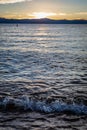 Waves crash on Lakeside Beach at Lake Tahoe with yellow clouds and hills in the distance