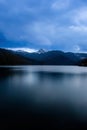 View of Lake Bolboci between the cloudy sky and in the distance the mountain ridges still bearing snow in late spring. Royalty Free Stock Photo