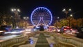 Bucharest ferris wheel for Christmas market, in front of the Parliament building, with cars going by at rush hour. Night, lights. Royalty Free Stock Photo