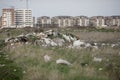 Piles of industrial and home waste lay on a field near inhabited blovks of flats