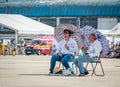 Two men with umbrellas sitting on chairs in the sun. Summer heat concept