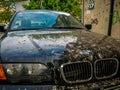 A BMW car illegaly parked on a sidewalk covered with bird droppings