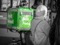 Bolt food courier on a bicycle carrying the green delivery bag. Young adult delivering the order