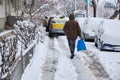 Bucharest sidewalk in Winter with illegally parked cars, covered with snow, and an yellow Dacia car blocking pedestrian access