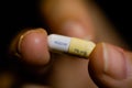 Close up image with the the fingers of a woman holding a Tamiflu capsule oseltamivir, an antiviral medication that blocks the Royalty Free Stock Photo