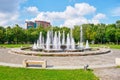 Artesian fountain in Alexandru Ioan Cuza IOR park with an apartments building and fresh green trees in the back.