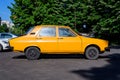 Bucharest, Romania - 5 June 2021: Old retro vivid yellow orange Romanian Dacia 1300 classic car parked in a street in a sunny