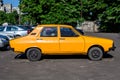 Bucharest, Romania - 5 June 2021: Old retro vivid yellow orange Romanian Dacia 1300 classic car parked in a street in a sunny