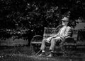 Bucharest/Romania - 05.21.2020 Lonely old man sitting on a bench in the Herestrau Park, Bucharest. Senior resting on a bench