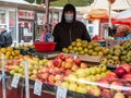 Bucharest/Romania - 11.20.2020: Man selling apples at a fruit stall . Fruit and vegetables market in Bucharest. Name and prices in