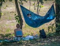 Bucharest/Romania - 09.16.2020: Man wearing a face mask relaxing in a hammock and reading a book