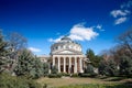 BUCHAREST, ROMANIA - MARCH 18, 2023: Ateneul Roman main facade in front of a park during a sunny afternoon. The Romanian Athenaeum
