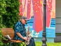 Bucharest, Romania - 06.04.2021: Senior street artist musician sitting on a bench in the park and playing at saxophone Royalty Free Stock Photo