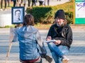 Street artist cartoonist or painter making portraits to people in Herestrau park Kink MIhai I,